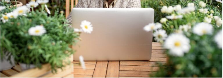 Photo d'un ordinateur au milieu de fleurs représentant le bien être que peut procurer la psychothérapie avec un psychologue bilingue français-espagnol